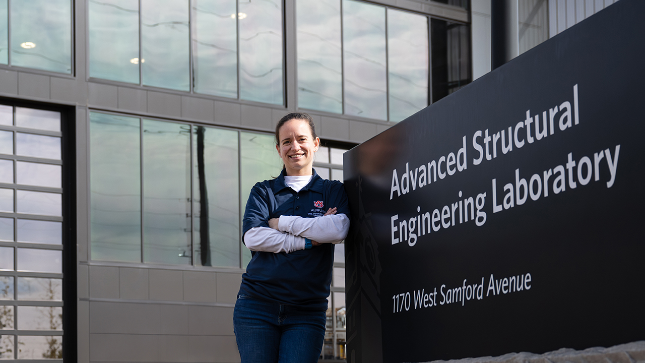 Amy Diekmann leans on the Advanced Structural Engineering Laboratory sign on Auburn University’s campus. 