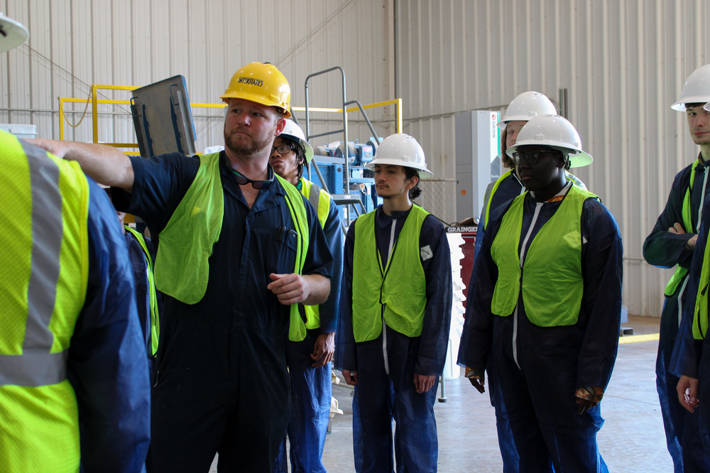 Students dressed in PPE attire while being shown the AU pellet mill