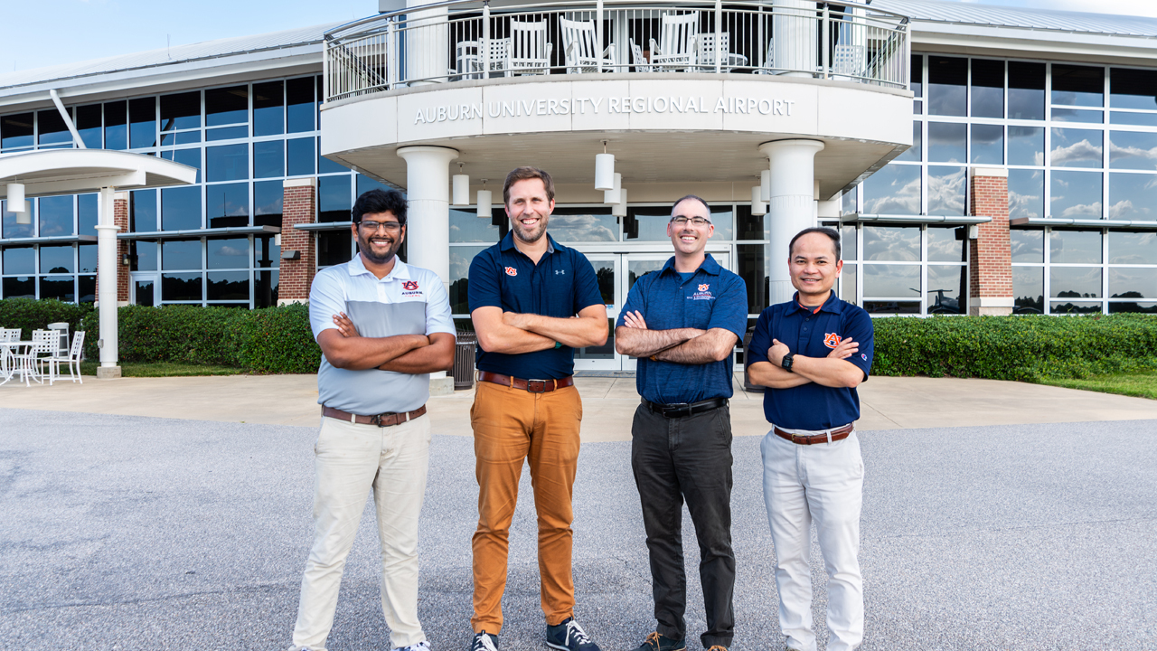 four men stand in front of building