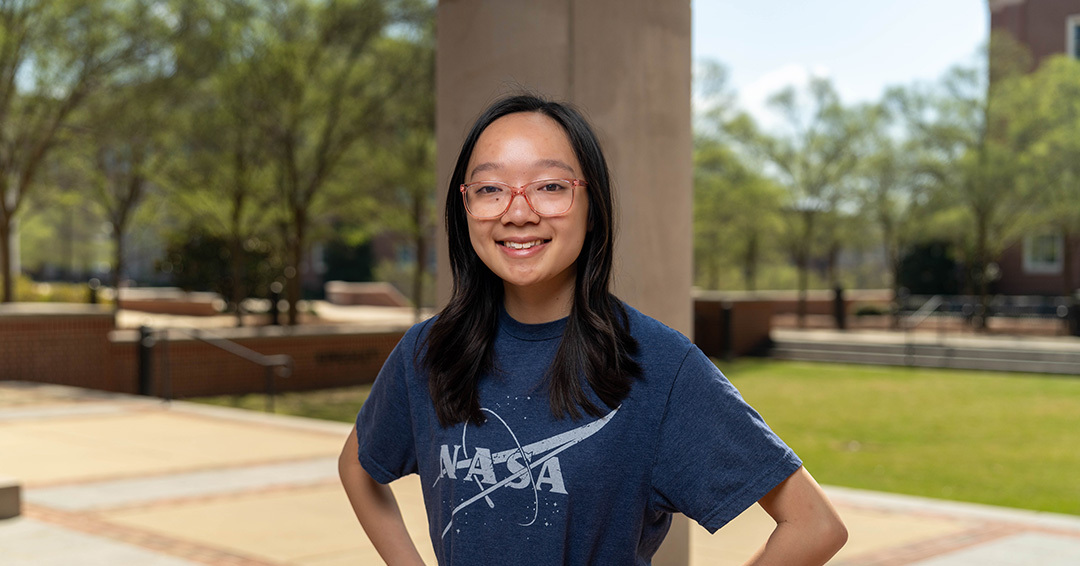 Auburn University mascot Aubie poses with participants and AAPT student chapter members at the NCAT Test Track 5K, with runners wearing race bibs and event t-shirts on the track.