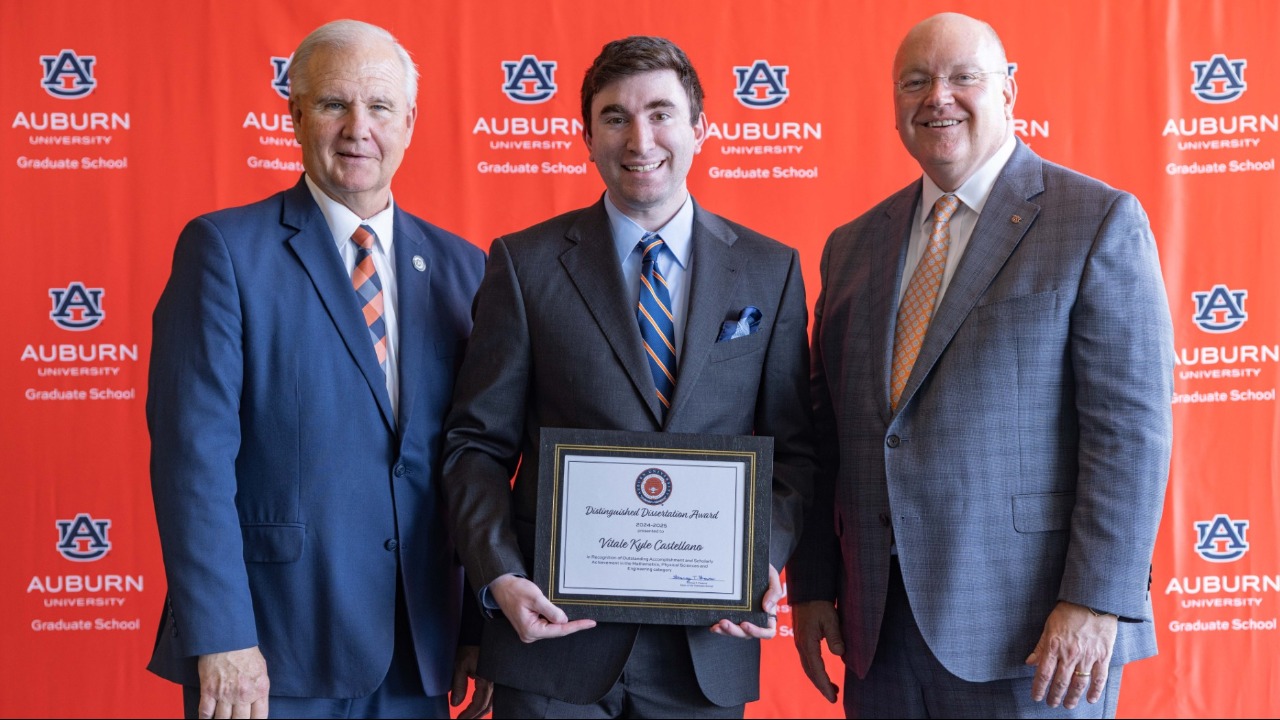 Kyle Castellano (center) poses with Graduate School Dean George Flowers (left) and President Christopher B. Roberts (right) while receiving the Graduate School's Distinguished Dissertation Award. Castellano is the only Auburn student to win both the Distinguished Dissertation Award and the Master's Thesis Award.
