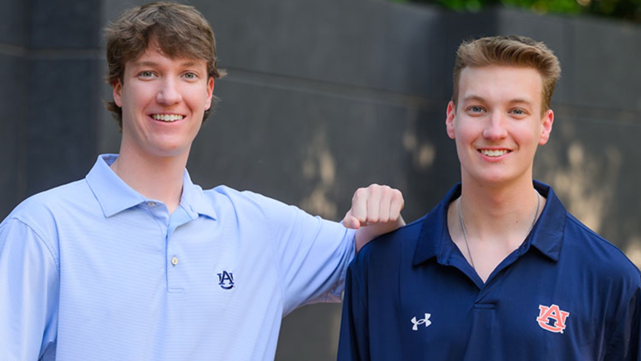 two men pose for a photo outside