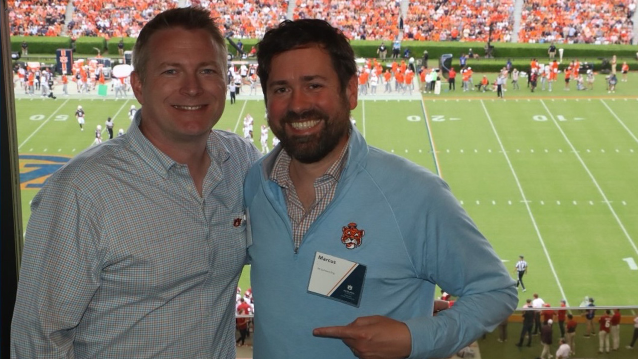 Two men stand in a football stadium.