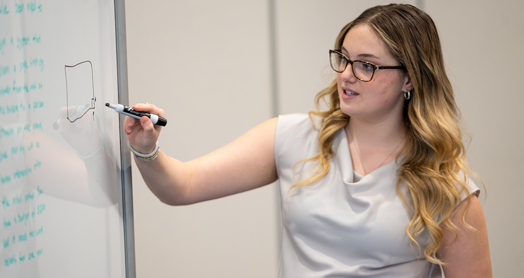 A woman writes on a whiteboard during a career development session.