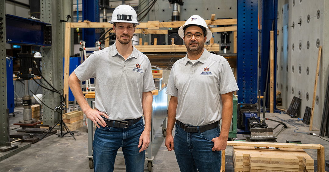 David Roueche and Kadir Sener stand inside Auburn’s Advanced Structural Engineering Laboratory wearing hard hats.