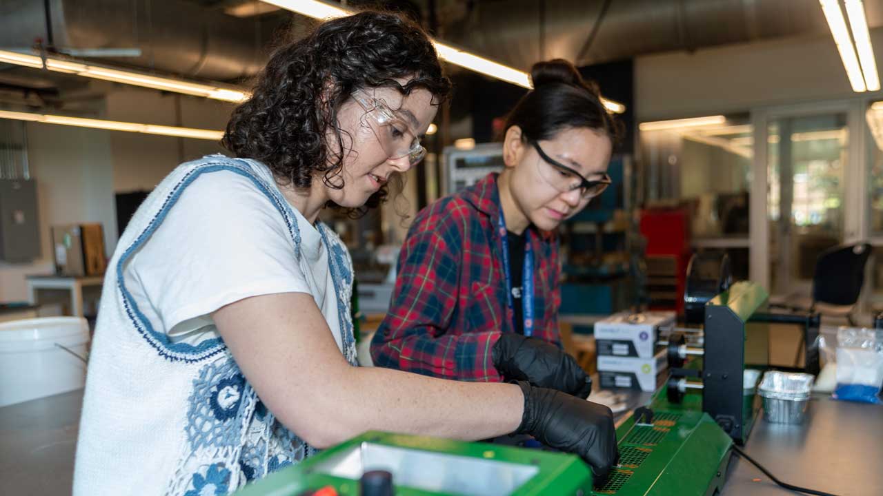 Maggie Nelson (left) and Yoorae Noh extrude recycled filament and feed it into a new spool.