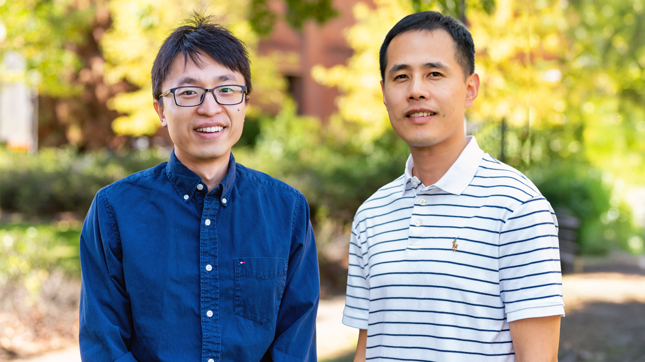 A woman smiles while shaking hands with a student in a green shirt at a career fair event, with colorful balloon decorations and people working in the background.