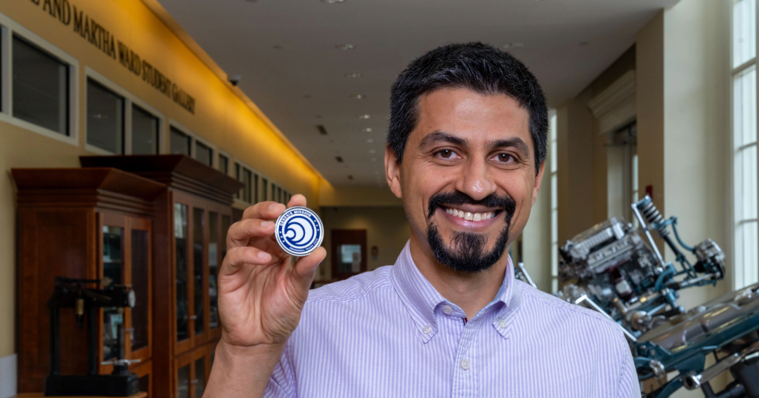 Reza Molaei holds a challenge coin given to Genesis Mission team members.