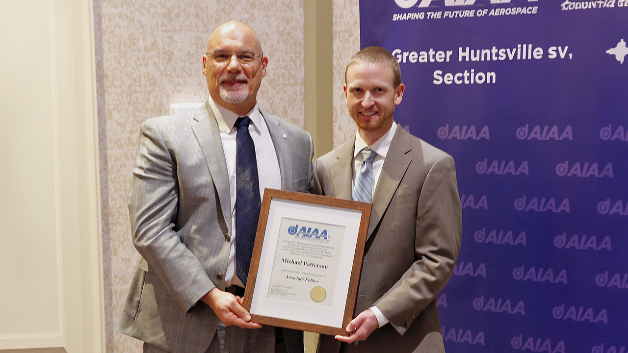 Two men posing for a photo with one man holding award