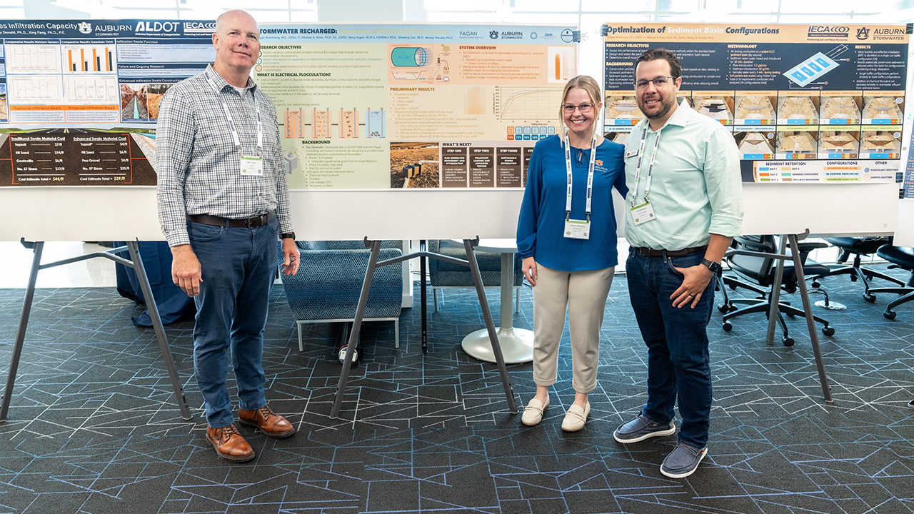 Three people pose for photo at poster presentation
