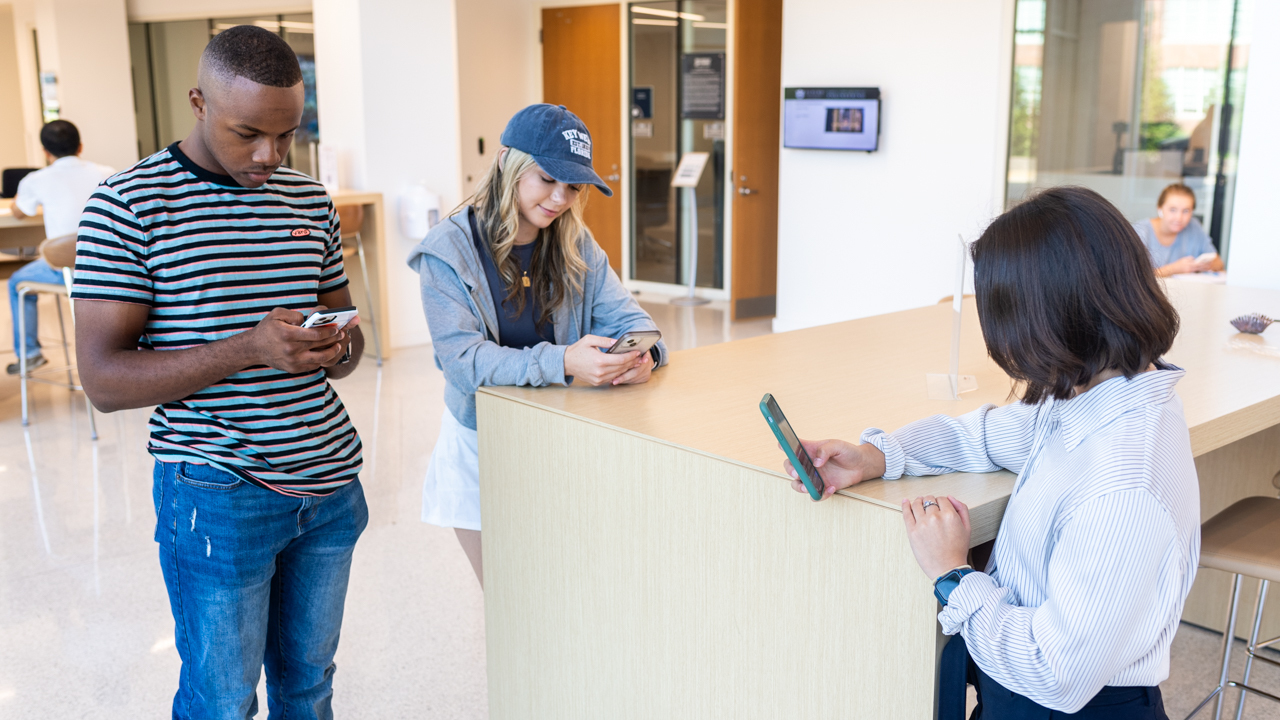three students look at their cell phones