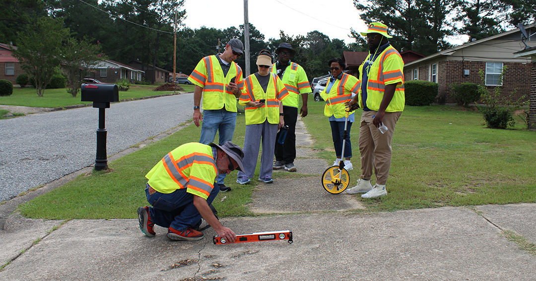 Transportation safety researchers and community partners assess sidewalk conditions along a residential street in West Alabama.