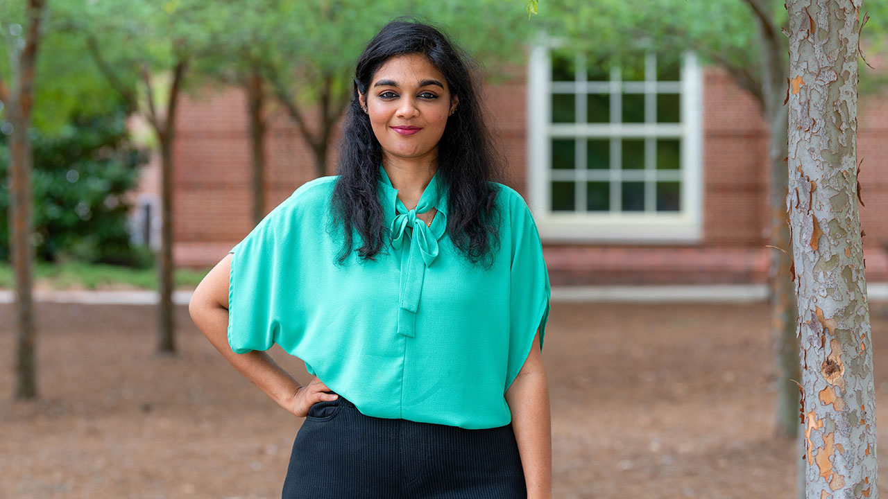 woman holds award standing in front of Auburn University backdrop.