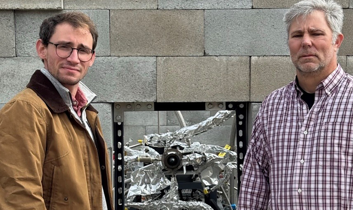 two men stand in front of a rocket