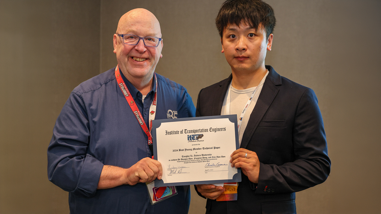 Two men pose for a photo while holding an award.