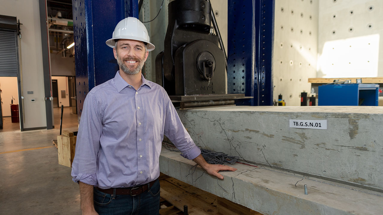 Man stands next to concrete with white hard hat