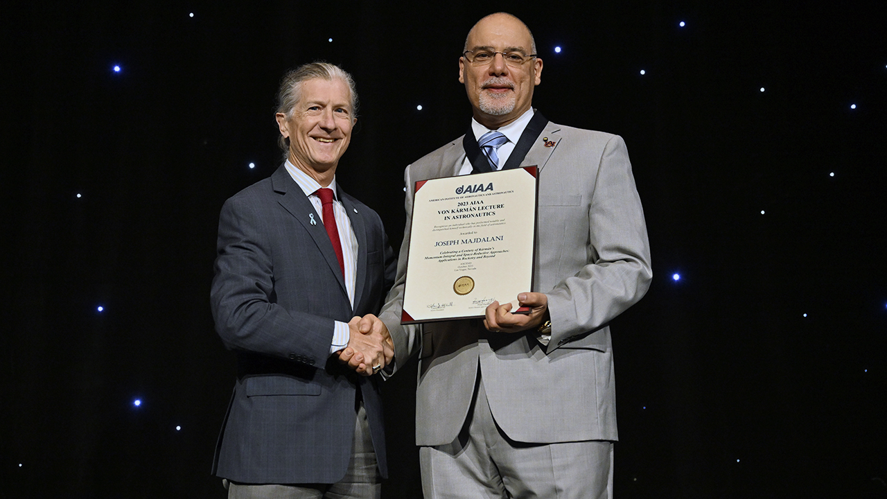  two men shaking hands on stage during award ceremony