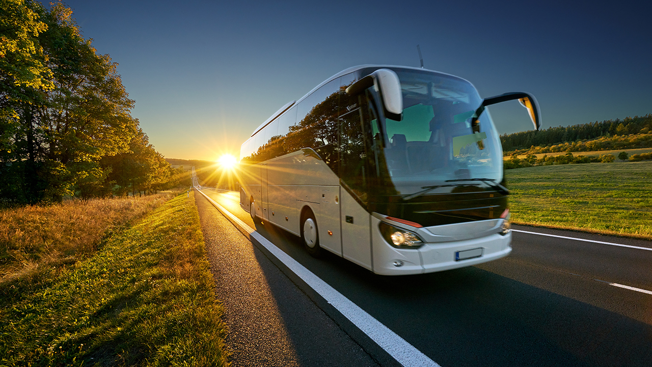 bus driving on run with sun behind it