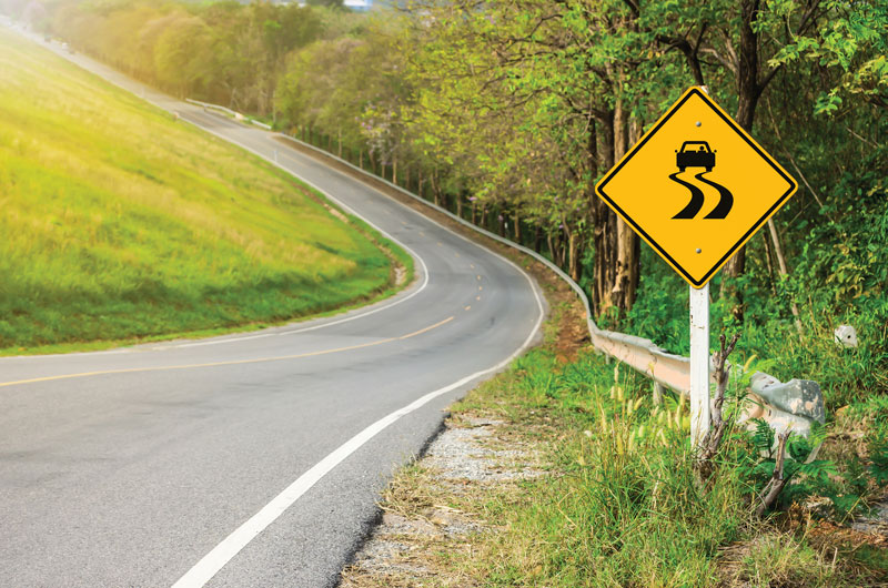 Scenic photo of curved road and sign.