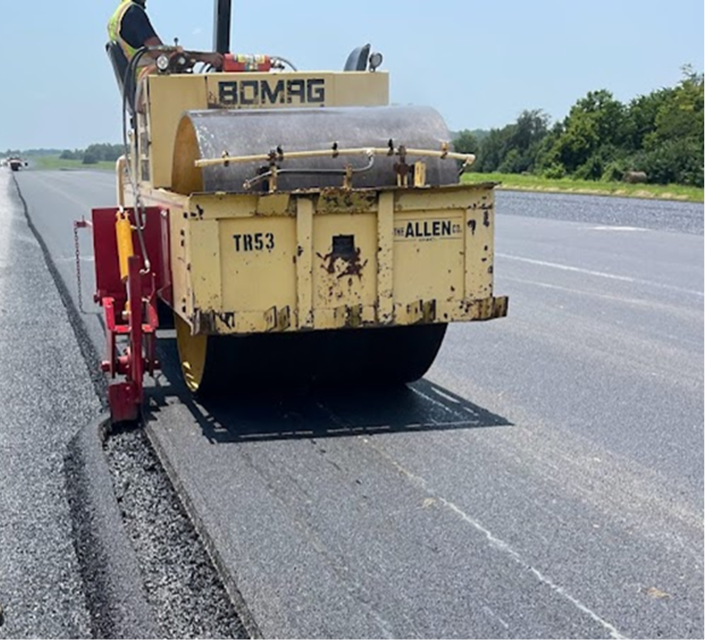 Cutting back the unconfined edge of a new pavement layer.