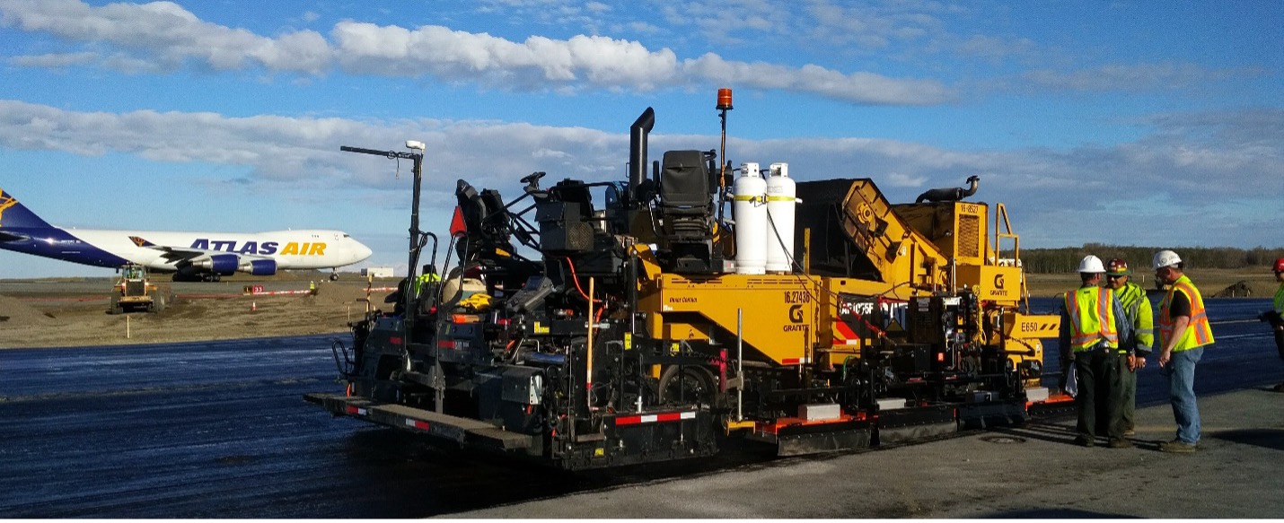 Paving an airport taxiway with a joint heater attached to the paver.